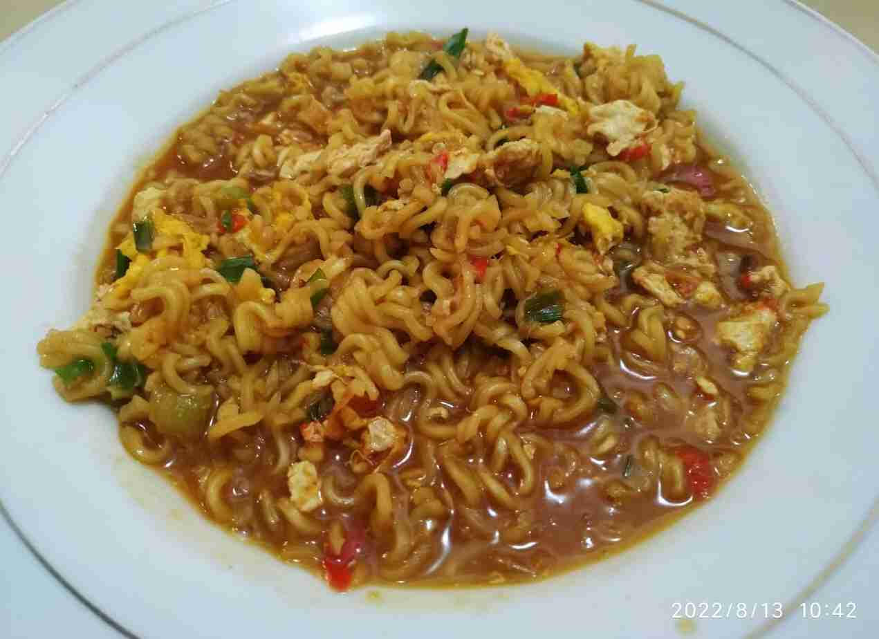 Mie goreng dengan sedikit kuah kental, sayuran segar, dan telur mata sapi setengah matang.